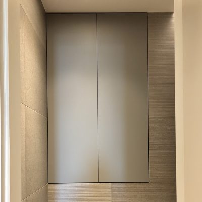 Ein minimalistisches Badezimmer, das Ruhe ausstrahlt, mit beigen Fliesen, einem wandmontierten Schrank und einem Toilettenpapierhalter an der rechten Wand.