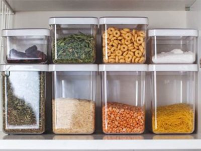 TOH_kuche Home Organizing - Acht durchsichtige Behälter mit verschiedenen trockenen Zutaten wie Getreide, Kräutern und Hülsenfrüchten sind ordentlich auf einem Regal angeordnet – ein Beweis für die Kunst der Haushaltsorganisation.